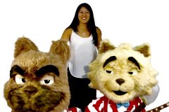 Custom animatronic bulldog mascot in business suit—furry head with grumpy expression, woman interacting at trade show booth