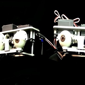 Custom industrial-rated animatronic eyes—white spheres with brown irises, metal mounts, blue LED accents, thick wiring—prototype pair on black background