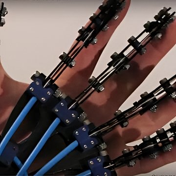 Custom robotic hand prototype in foreground—detailed fingers and joints—compared to human hand behind for scale, engineering demo