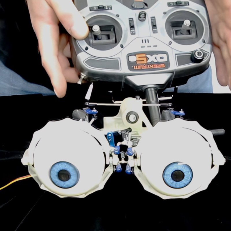 Close-up of realistic animatronic puppet eyes with bright blue irises and professional radio control system with multiplexing box